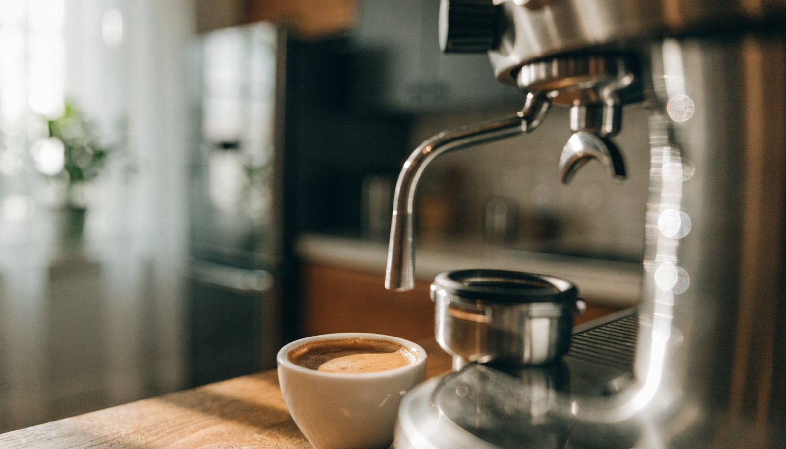 Home espresso machine pulling a shot on a wooden kitchen counter