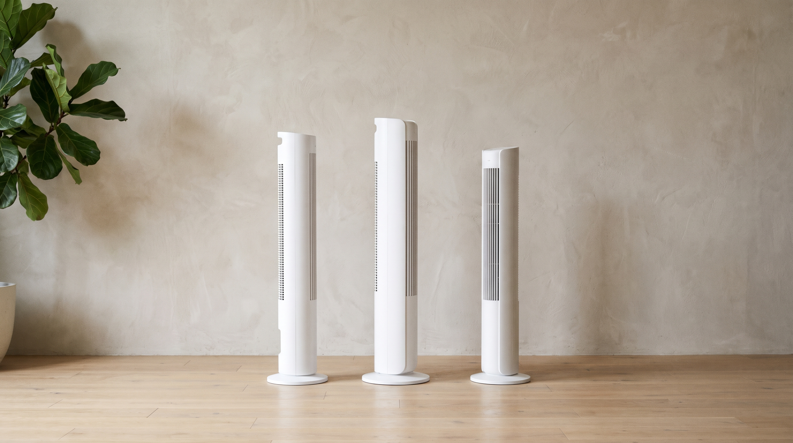 Three tower air purifiers of different sizes side by side on a wooden floor